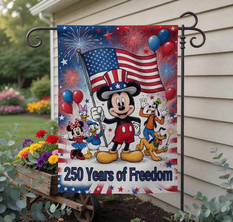 K&ouml;nnte beinhalten: Eine Gartenflagge mit Micky Maus, die eine amerikanische Flagge h&auml;lt, mit Feuerwerk und Luftballons im Hintergrund. Weitere Disney-Figuren sind ebenfalls vorhanden. Auf der Flagge steht "250 Years of Freedom."