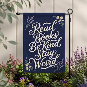 May include: A rectangular navy blue garden flag featuring the white cursive text Read Books Be Kind Stay Weird. The design is decorated with illustrations of purple lavender sprigs and white daisy flowers in the corners of the fabric banner.