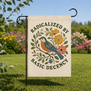 May include: A rectangular garden flag featuring a blue and orange bird perched on a branch surrounded by yellow, orange, and blue flowers and green leaves. The text RADICALIZED BY BASIC DECENCY is printed in dark green letters above and below the bird.