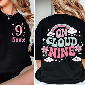 Peut inclure: Sweat-shirt noir avec le chiffre 9 et le mot "Name" en rose. Le dos du t-shirt indique "On Cloud Nine" avec un arc-en-ciel, des fleurs et des nuages. Le motif est rose, vert menthe et blanc.