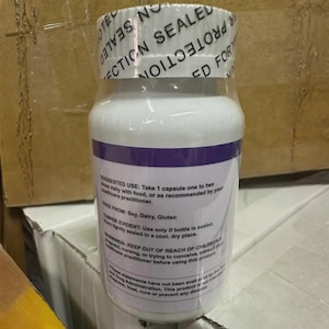 Puede incluir: Una botella de suplemento blanca con una banda morada y envoltura retr&aacute;ctil transparente. La etiqueta incluye instrucciones de uso y advertencias. La botella est&aacute; sellada con un sello a prueba de manipulaciones.