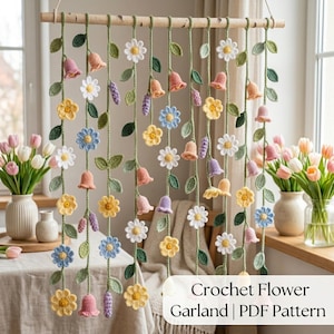 Könnte beinhalten: Eine gehäkelte Blumengirlande mit verschiedenen bunten Blumen und glockenförmigen Blüten, die an einer Holzstange hängen. Die Girlande zeigt gelbe, blaue, weiße und rosa Blumen mit grünen Blättern und Stielen. Der Text "Crochet Flower Garland | PDF Pattern" ist sichtbar.