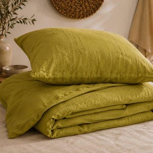 May include: A chartreuse green bedding set consisting of a rectangular pillowcase and a folded duvet cover. The fabric has a visible textured weave and a matte finish. The pillowcase rests on top of the neatly folded duvet cover.