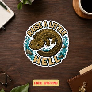 May include: A circular sticker featuring a brown salamander swimming in blue water with gray rocks. The text "RAISE A LITTLE HELL" is printed in bold, tan, block letters around the top and bottom edges of the illustration on a white background.