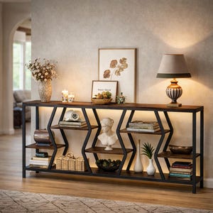 May include: A long, dark wood and metal console table with built-in lighting. The table features a geometric design with multiple shelves displaying books, vases, and decorative items. A lamp and artwork are on top, creating a stylish display.