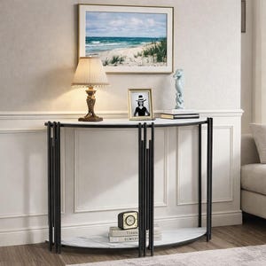 May include: A half-moon console table with a white marble top and black metal frame. The table is decorated with a lamp, framed art, a seahorse figurine, and a clock. A framed picture of a woman in a hat is also on the table.