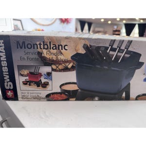 Könnte beinhalten: Ein schwarzes Montblanc Fondue-Set mit 15 Teilen, darunter ein gusseiserner Topf und Gabeln. Die Box zeigt das Swissmar-Logo und französischen Text. Das Set ist zum Servieren von Fondue konzipiert und enthält kleine Schalen.