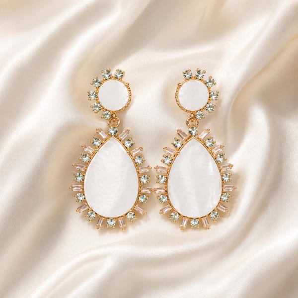 May include: A pair of gold-tone drop earrings featuring a circular top and a larger pear-shaped bottom, both inlaid with smooth white shell-like material and surrounded by a halo of small, clear, baguette-cut crystals set in metal.