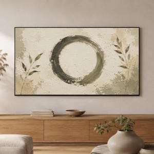 Op de afbeelding: Een rechthoekig wandkunstwerk met een grote, getextureerde donker olijfgroene cirkel in het midden op een crèmekleurige achtergrond. Twee delicate, bladerrijke takken in gedempte groentinten flankeren de cirkel, in een dunne, zwarte lijst.