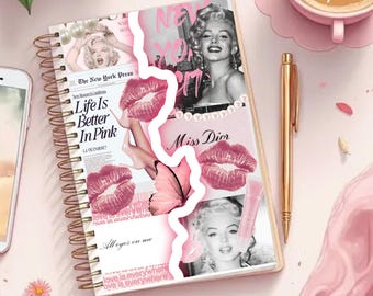 May include: A spiral-bound notebook with a collage design featuring Marilyn Monroe, pink lipstick, and the text "Life Is Better In Pink." A gold pen and a cup of coffee are also visible.