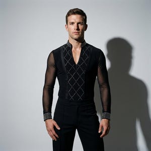 Puede incluir: Camisa de baile negra con cuello en V y mangas transparentes. La camisa presenta un patrón de diamantes en la parte delantera y detalles con tachuelas en el cuello y los puños. Conjunto de baile formal.