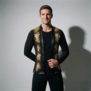 Puede incluir: Camisa y pantalón negros de manga larga con un chaleco decorativo. El chaleco presenta bordados florales dorados y plateados y un ribete de satén negro. El atuendo está diseñado para baile o espectáculos.