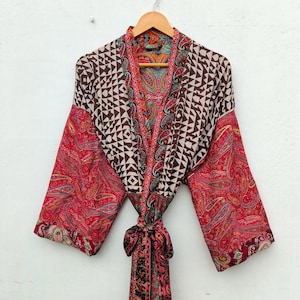 May include: A long-sleeved kimono robe featuring a mix of patterns, including a brown and white geometric print on the upper section and a vibrant red paisley design on the sleeves and lower body, finished with a matching fabric tie belt at the waist.