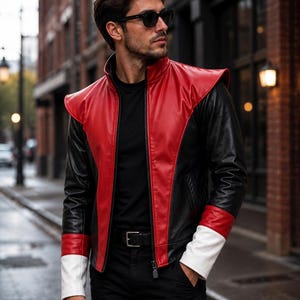 May include: A color-blocked jacket featuring a red center panel, black sleeves, and white cuffs. The jacket has a high collar, a front zipper closure, and extended shoulder panels. It is worn over a black shirt with a black belt and black pants.