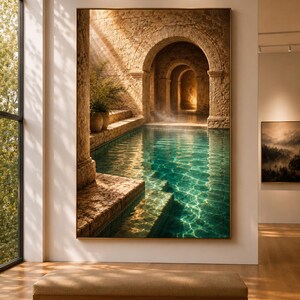 May include: A large rectangular wall art print featuring a stone archway leading to a sunlit indoor pool with turquoise water. The scene includes textured stone pillars, a potted plant on a ledge, and light rays reflecting on the water surface.