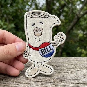 May include: Embroidered patch featuring a cartoon depiction of a bill document with a face, arms, and legs. The bill wears a red sash and a round emblem that says "BILL" in white letters on a blue and red background. The patch has a cream-colored background and a stitched border.
