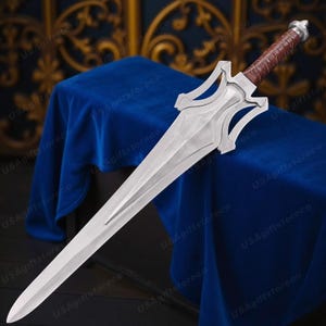 May include: A silver sword with a brown leather-wrapped handle. The blade is long and double-edged, with a decorative hilt. The sword is displayed on a blue surface.