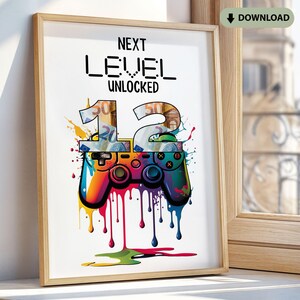 Puede incluir: Impresión artística enmarcada con el texto "NEXT LEVEL UNLOCKED" sobre un gráfico de mando colorido. El número "12" está estilizado con dinero en su interior. Gotas de pintura brillantes gotean del mando, añadiendo un toque vibrante.