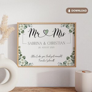 May include: A framed wedding sign with the words "Mr & Mrs" in elegant script, along with the names "Sabrina & Christian" and the date "20. August 2025". The sign is decorated with floral accents and a heart symbol.