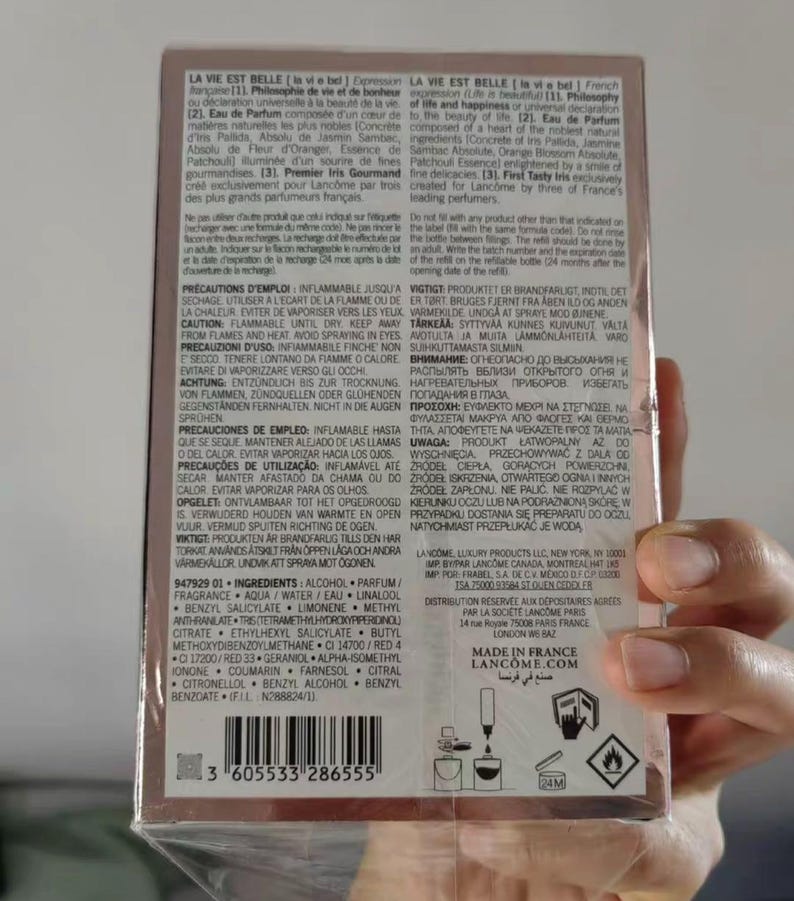 May include: A box of Lanc&ocirc;me La Vie Est Belle perfume. The packaging is a light pink with text in multiple languages. The bottom of the box has a barcode and the text "MADE IN FRANCE".
