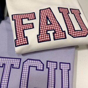 Moletom personalizado com bordado xadrez vichy, gola redonda com apliques personalizados estilo universitário, pulôver minimalista com patchwork estilo faculdade.