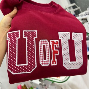 Moletom personalizado com patchwork bordado, moletom universitário personalizado com gola redonda, moletom com apliques em tecidos mistos, suéter com estética universitária.