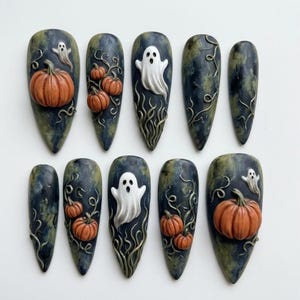 May include: A set of ten almond-shaped press-on nails featuring a dark, mottled blue and green base. The designs include raised 3D orange pumpkins, white ghosts with black eyes and mouths, and swirling vine-like accents across the surfaces.