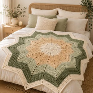 May include: A star-shaped crochet blanket featuring a gradient pattern of cream, light beige, and sage green yarn. The circular center transitions into twelve pointed rays, with each color section worked in a textured stitch pattern.