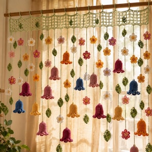 May include: A crochet window valance featuring a light green lattice top border with hanging vertical strands. The strands are decorated with small multi-colored flowers and larger bell-shaped blossoms in shades of blue, pink, and yellow.
