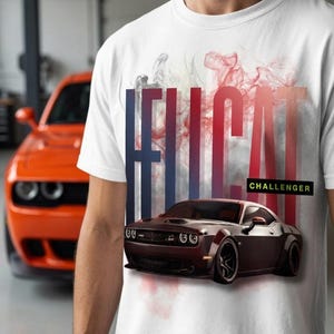 Könnte beinhalten: Ein weißes T-Shirt mit einem Grafikdruck eines dunkel gefärbten Dodge Challenger Autos. Das Design zeigt das Wort HELLCAT in großen, vertikalen, farbverlaufenden Buchstaben, überlagert mit roten und grauen Raucheffekten sowie dem Wort CHALLENGER.