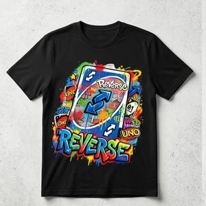 May include: Black t-shirt featuring a colorful graphic of an Uno Reverse card with blue arrows and the word "REVERSE" in graffiti style. The design includes other Uno card elements and spray paint effects.