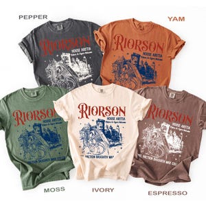 Puede incluir: Una colecci&oacute;n de camisetas de manga corta en varios colores, incluyendo gris, naranja, verde, marfil y marr&oacute;n. Cada camiseta presenta un dise&ntilde;o gr&aacute;fico con la palabra "RIORSON" en rojo, junto con una ilustraci&oacute;n de un castillo y un drag&oacute;n. Tambi&eacute;n se ve el texto "HOUSE ARETIA".