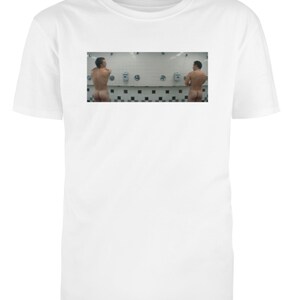 Könnte beinhalten: Weißes T-Shirt mit einem kleinen Bild von zwei Personen, die in einer öffentlichen Toilette duschen. Das Bild zeigt die Personen von hinten, wobei die Duschköpfe und Wasserhähne sichtbar sind. Der Hintergrund ist eine geflieste Wand.