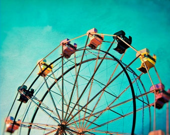 May include: A colorful Ferris wheel with gondolas against a bright turquoise sky. The wheel is made of metal and has a black rim. The gondolas are painted in various colors, including yellow, pink, and black.