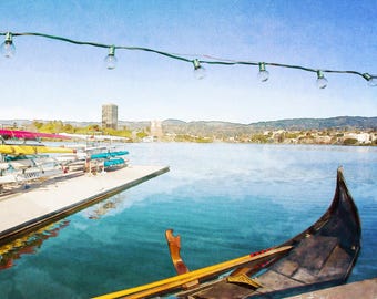May include: A watercolor-style image of a gondola on a lake, with a wooden dock and other boats in the background. The sky is a clear blue, and a string of lights hangs overhead. The gondola is black and brown, with a wooden oar.