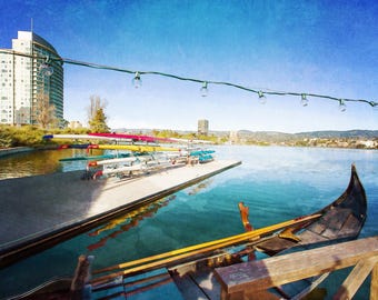 May include: A scenic waterscape featuring a gondola and several rowboats docked at a pier. The water reflects the blue sky and surrounding buildings. Overhead, a string of lights adds a decorative touch to the scene.
