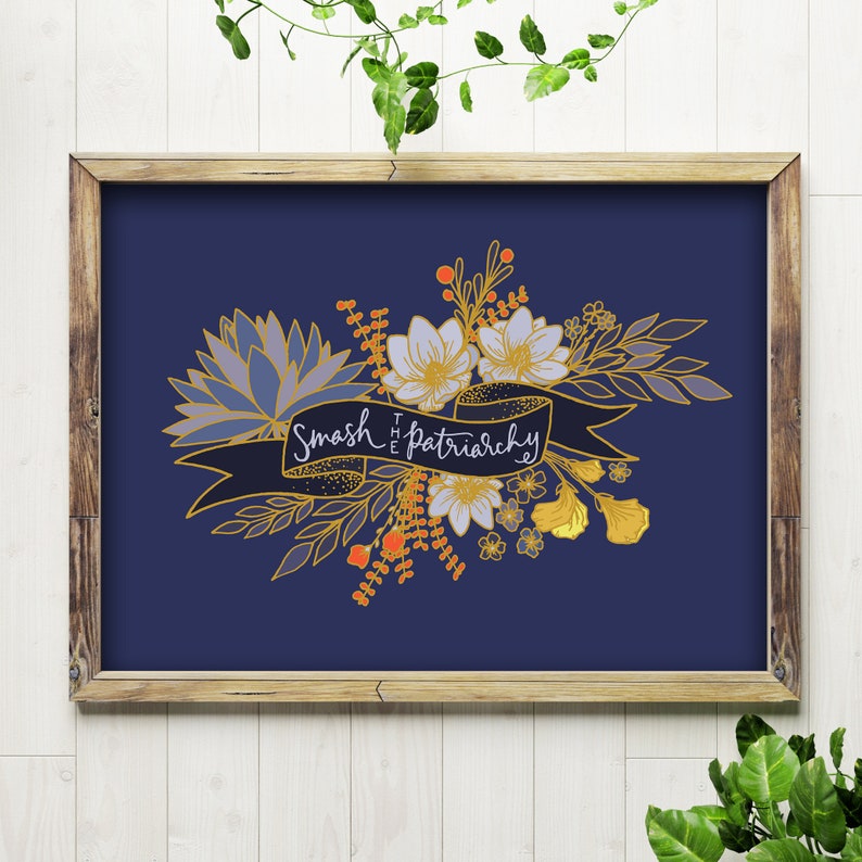 May include: A framed art print featuring a navy blue background with a floral design in shades of blue, gold, and orange. A banner across the flowers reads "Smash the Patriarchy". The frame is made of wood.