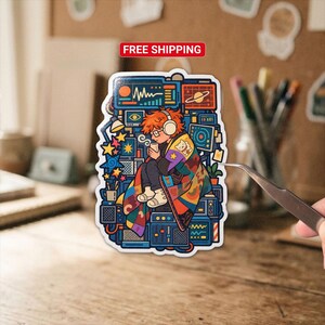 May include: A die-cut sticker featuring a person with orange hair wearing headphones and a colorful patterned blanket, sitting amidst a stack of blue electronic equipment and monitors. The sticker includes the text FREE SHIPPING at the top.