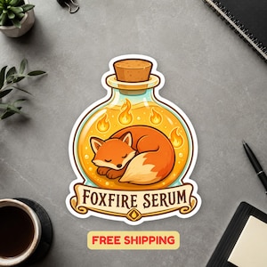 May include: A sticker featuring a round glass bottle with a cork stopper containing a sleeping orange fox surrounded by small yellow flames. Below the bottle, a banner displays the text FOXFIRE SERUM in bold, dark brown capital letters.