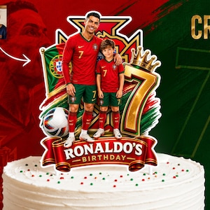 May include: A custom cake topper featuring a graphic of Cristiano Ronaldo and a child in red and green Portugal soccer uniforms, a soccer ball, a gold crown, the number 7, and a red banner with the text RONALDO'S BIRTHDAY on a white cake.