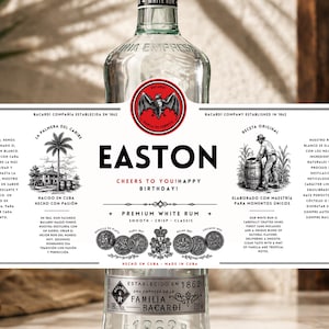 Puede incluir: Una botella de vidrio transparente de ron blanco con una etiqueta blanca personalizada con texto y gráficos en negro. La etiqueta muestra el nombre EASTON, un logo de murciélago, una palmera, una persona con un barril y varios iconos de medallas con el texto CHEERS TO YOU! HAPPY BIRTHDAY!