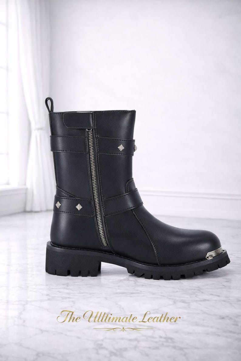 May include: Black leather ankle boot with a silver zipper, straps, and diamond-shaped studs. The boot has a chunky sole and a metal accent on the toe. The text "The Ultimate Leather" is at the bottom.