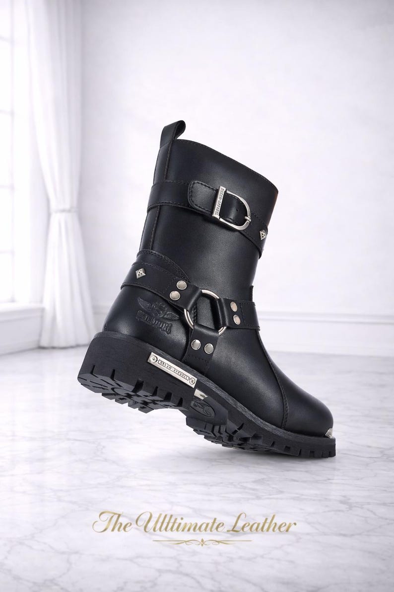 May include: Black leather boot with silver-tone buckles and studs. The boot features a chunky sole and a harness-style strap. The text "The Ultimate Leather" is at the bottom of the image.