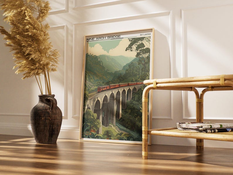 May include: A framed print of the Nine Arch Bridge in Sri Lanka. The artwork shows a red train crossing the bridge, set against green mountains and a blue sky. The print is in a wooden frame.