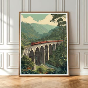 May include: A framed art print showing a red train on a stone bridge with arches, set in a green valley with mountains. The artwork has a vintage travel poster style, reminiscent of classic railway travel.
