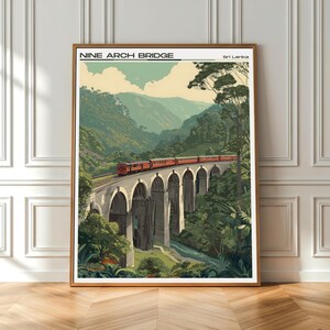 May include: A framed print of the Nine Arch Bridge in Sri Lanka. The image shows a red train on the bridge, set against a backdrop of green hills and trees. The text "NINE ARCH BRIDGE" is displayed at the top.