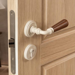 May include: Close-up of a wooden door with a cream-colored handle and a dark brown wooden lever. The door also features a cream-colored keyhole cover and a silver-colored door latch.