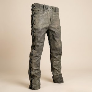 Puede incluir: Un pantalón gris de aspecto desgastado con un diseño de cordones a lo largo de las costuras laterales exteriores. El pantalón incluye una cintura con trabillas, cierre de botón y bolsillos delanteros con remaches metálicos. Acabado texturizado.