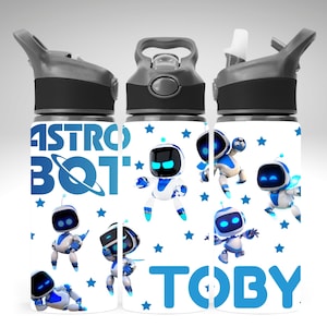 May include: Three water bottles with black lids and grey accents. The bottles have a white background with blue stars and cartoon robots. The text "ASTRO BOT" and "TOBY" are printed in blue.