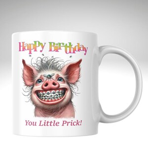 May include: White ceramic mug with a cartoon pig illustration. The pig has braces and a fly on its nose. The mug features the text "Happy Birthday" and "You Little Prick!" in pink.